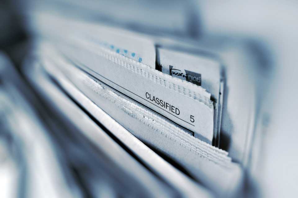 Página clasificada de un periódico en blanco y negro, enfoque selectivo